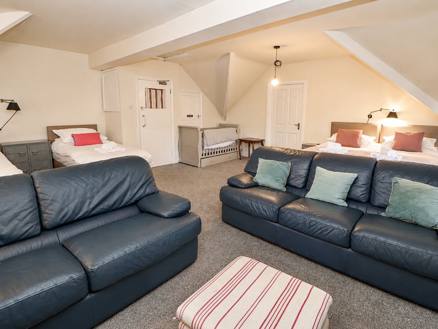 Second floor suite at Heather Brae with multiple beds, blue leather sofas and travel cot